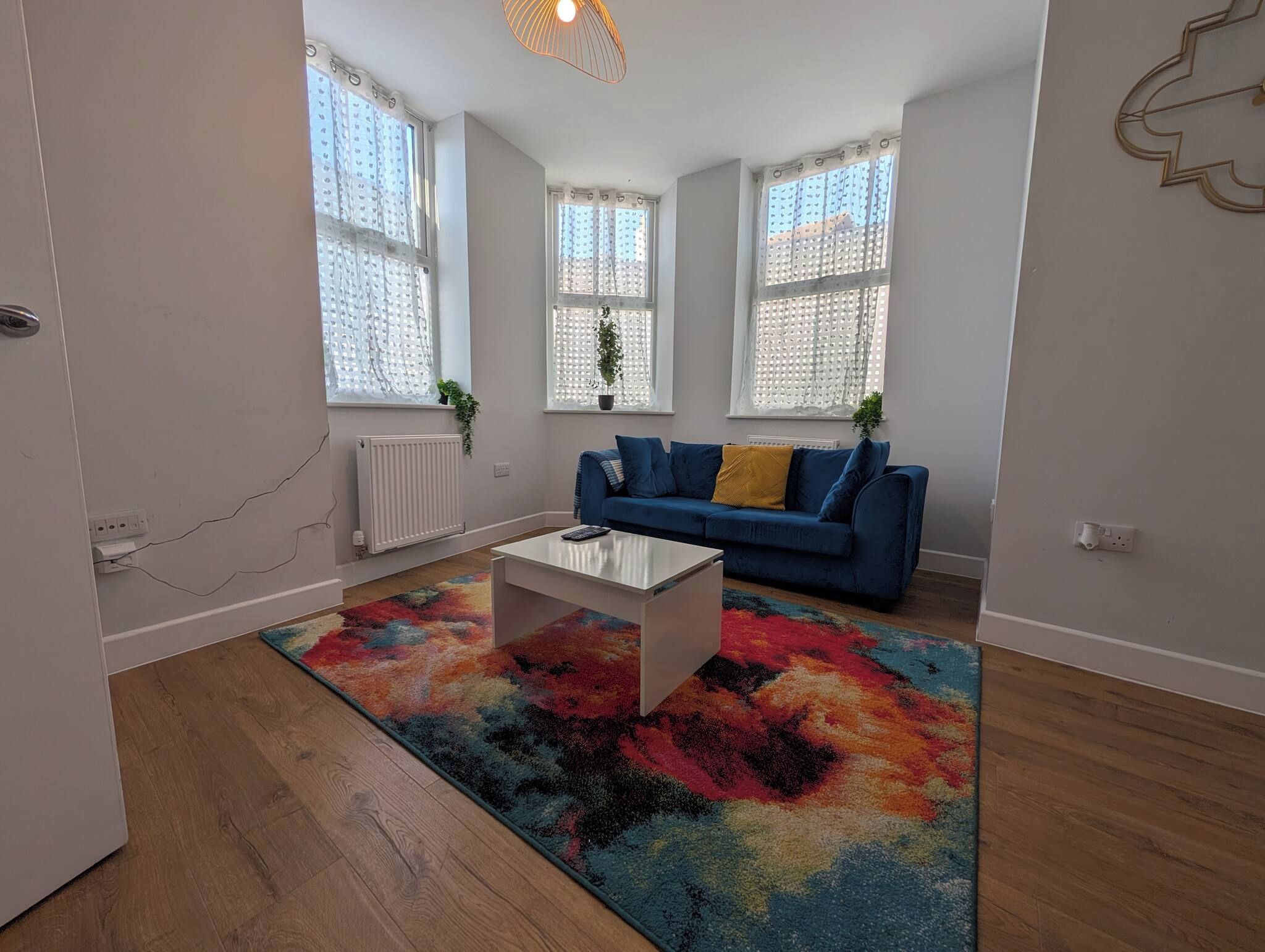 A modern living room with a blue sofa, a white coffee table, and a colorful rug.