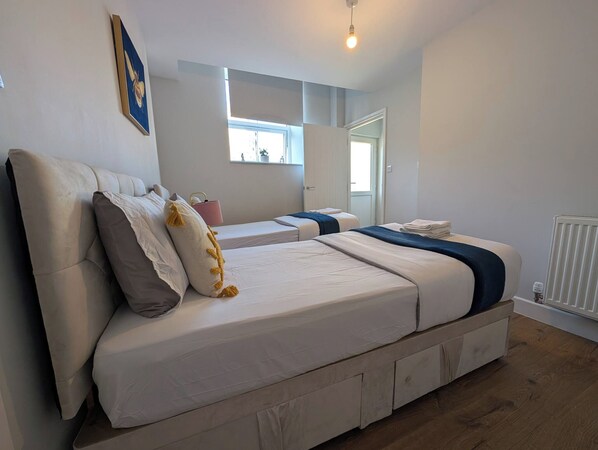 A modern bedroom with a large bed, a small table, a window, and a radiator.