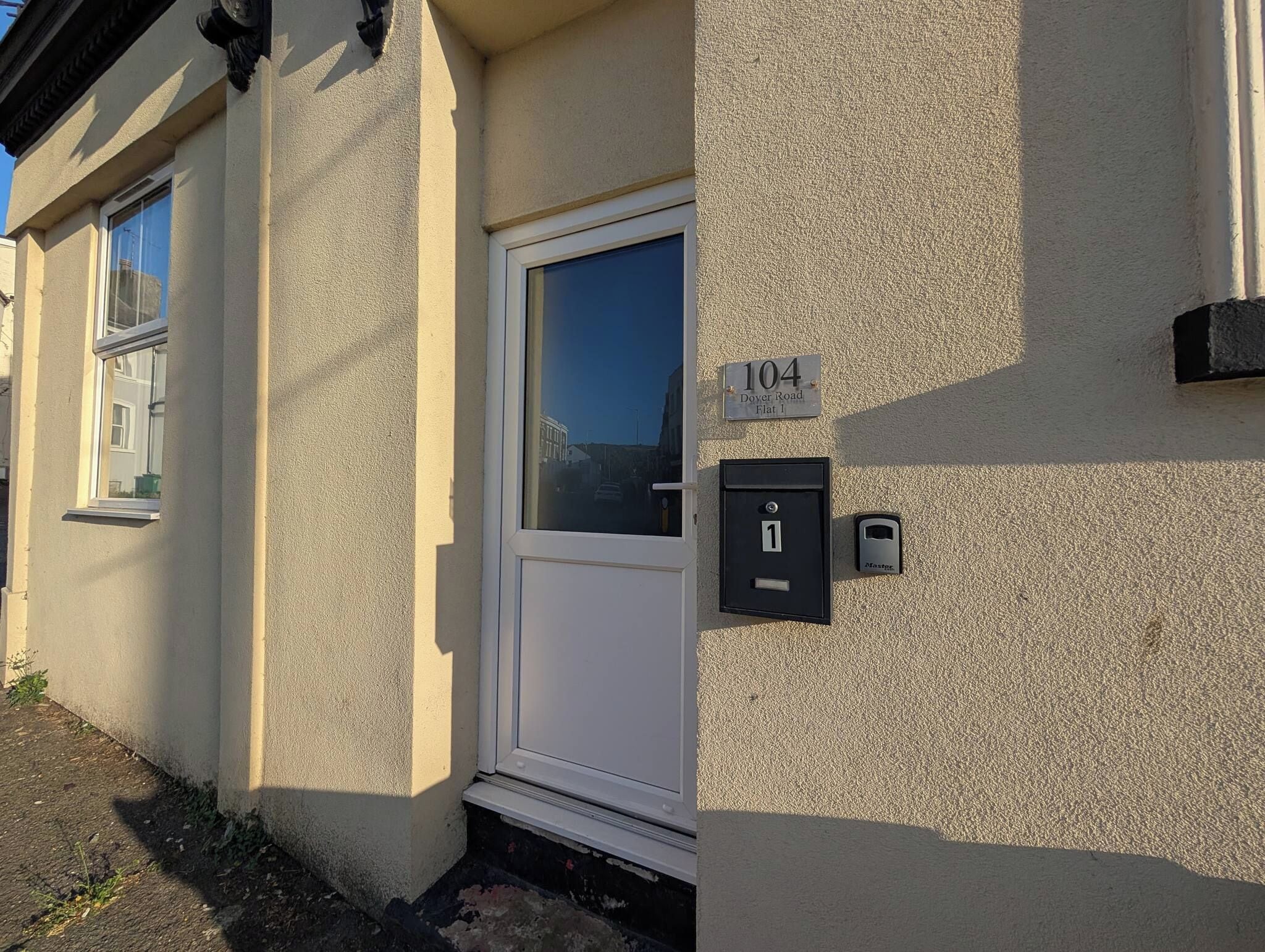 A building with a white door, a mailbox, and a number sign indicating the address.