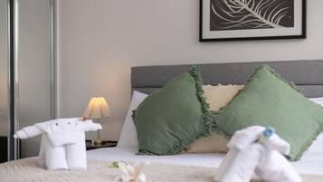 A neatly made bed with two pillows, a bedside lamp, and a framed artwork on the wall.