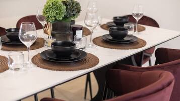 A dining table set with black plates, bowls, and glasses, accompanied by a green plant centerpiece.