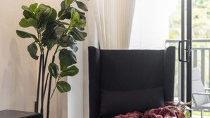 Un moderno salón con un sillón negro, una mesa redonda con una manta roja y una planta en maceta.
