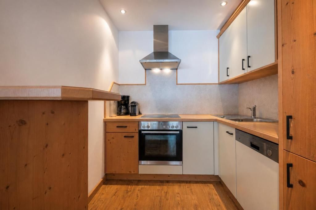 A compact kitchen with wooden cabinets, a stainless steel oven, and a built-in range hood.