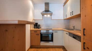 A compact kitchen with wooden cabinets, a stainless steel oven, and a built-in range hood.