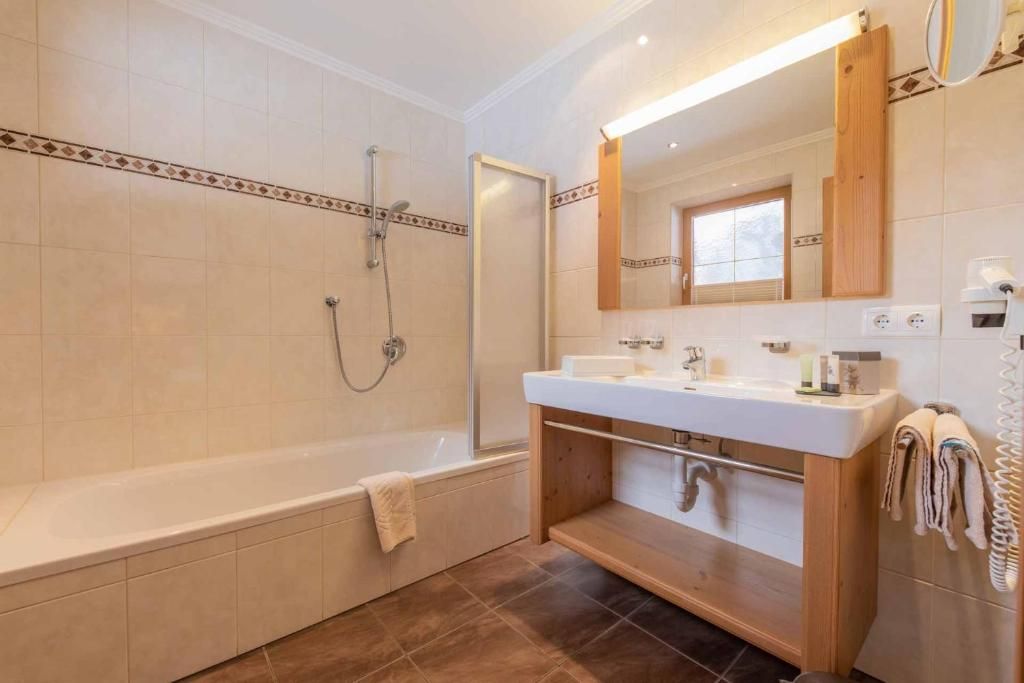 A modern bathroom with a bathtub, a shower, and a vanity with a mirror.