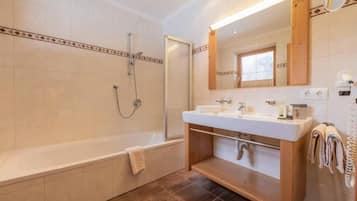 A modern bathroom with a bathtub, a shower, and a vanity with a mirror.
