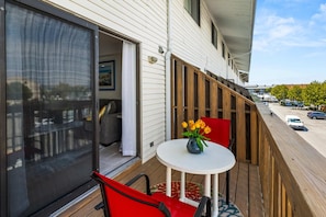 Ein Balkon mit Tisch, Stühlen und einer Blumenvase.