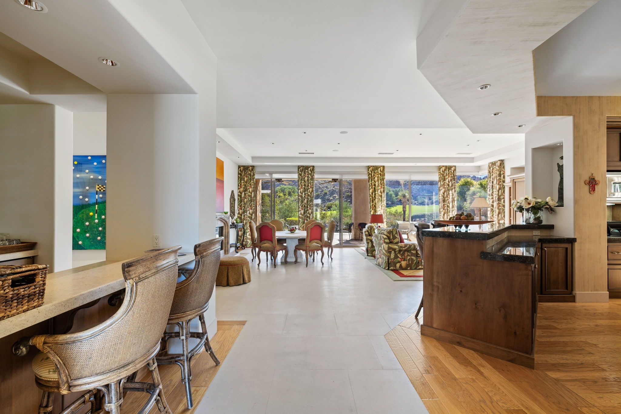 Un vaste espace dédié à la salle à manger, avec une longue table et des chaises, un coin cuisine doté d’un comptoir en bois et de grandes fenêtres offrant une vue sur l’extérieur.