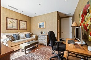 A modern living room with a sofa, a desk with a computer, a chair, and a patterned rug. - The Reserve - Luxury 4-Bedroom Retreat Plus Office in Peaceful Indian Wells (Indian Wells)