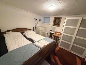 Une chambre à coucher avec un lit double, une table de chevet, une chaise, un radiateur, un miroir et une armoire.