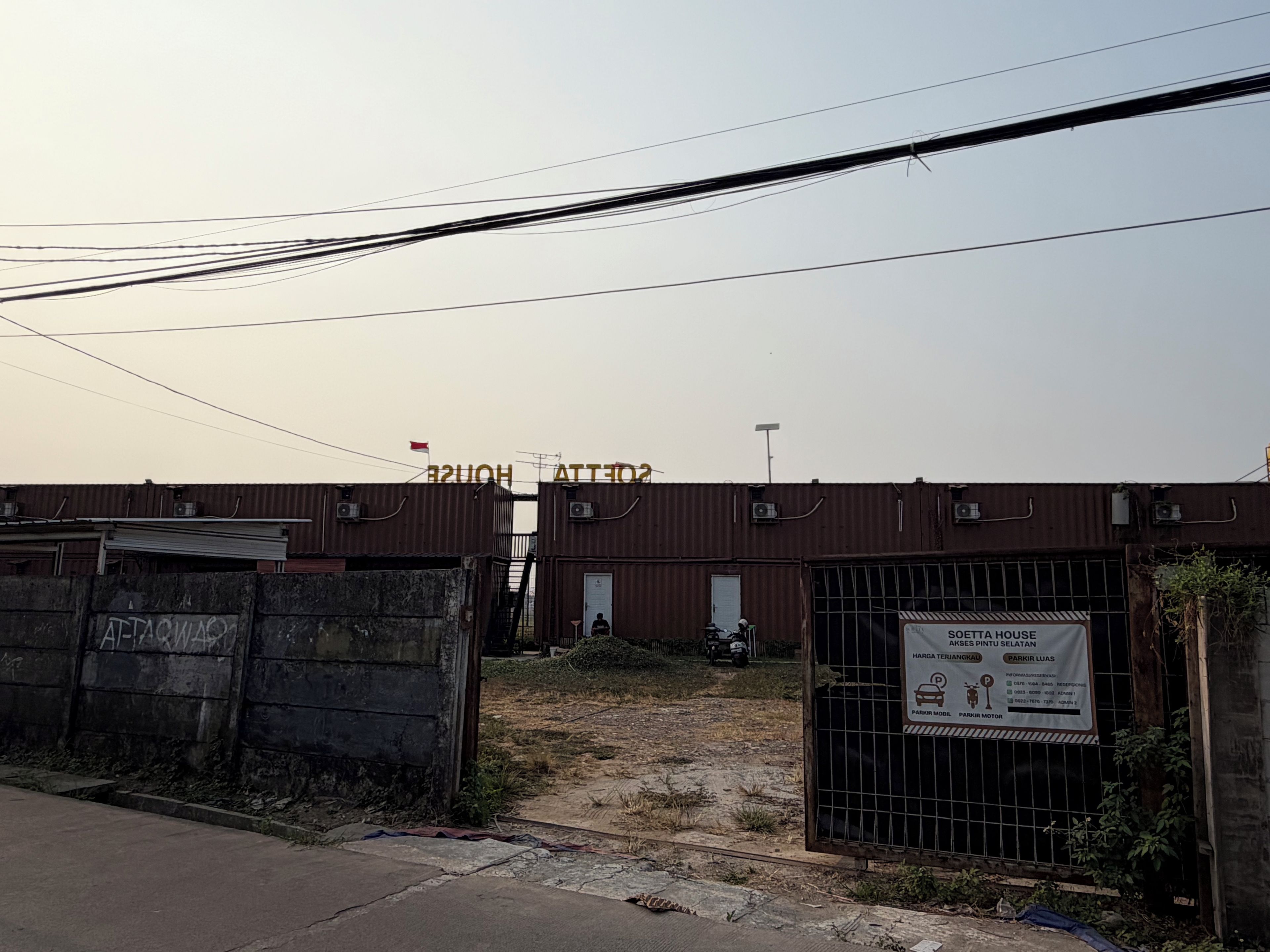 Zona industrial cerrada con un letrero que indica un estacionamiento para un hotel.