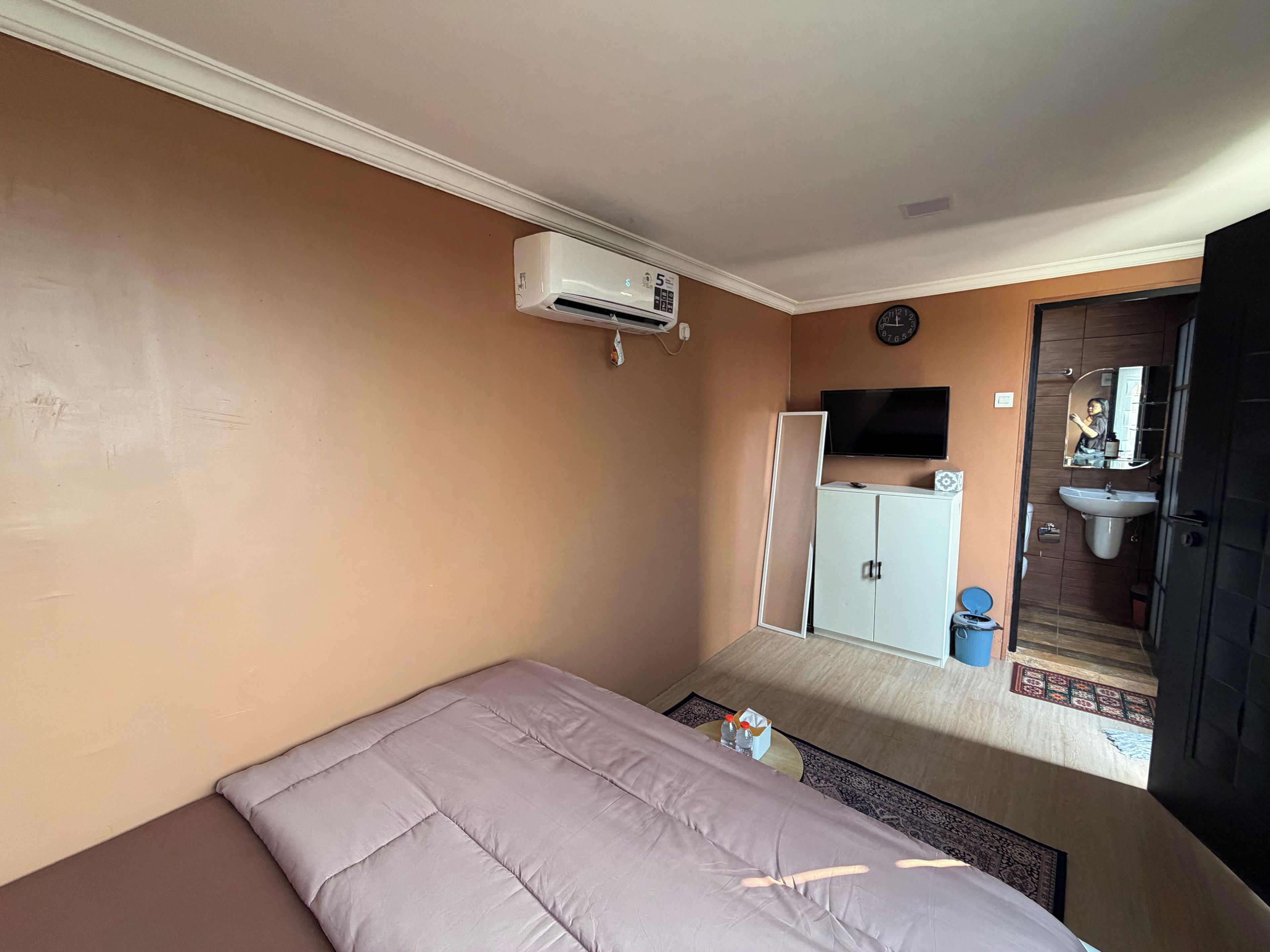 Ein Schlafzimmer mit Bett, Kleiderschrank, Fernseher und angrenzendem Badezimmer.