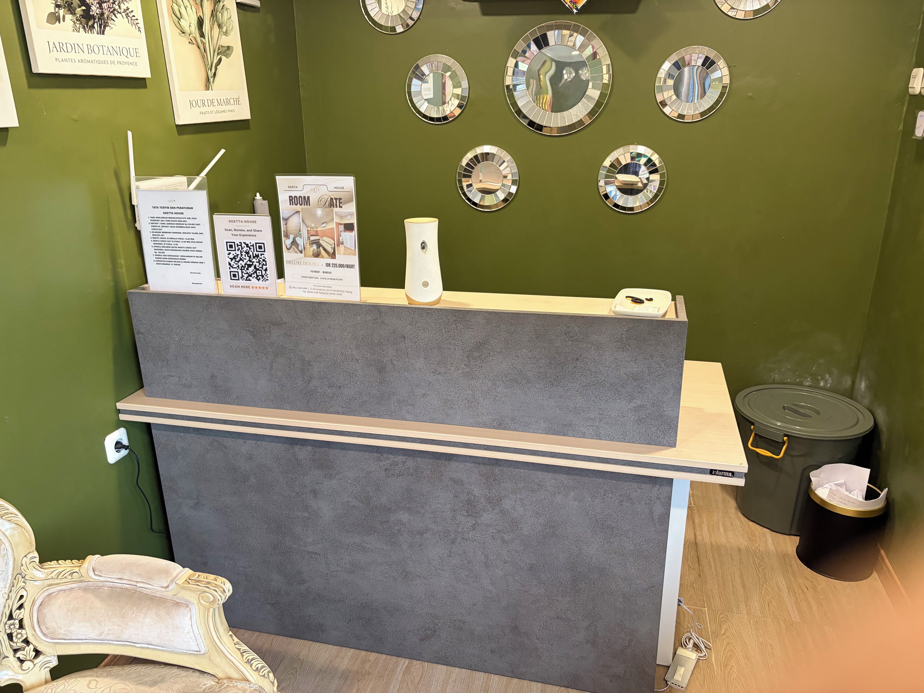 A reception desk with a grey counter, a white chair, and a small trash bin.