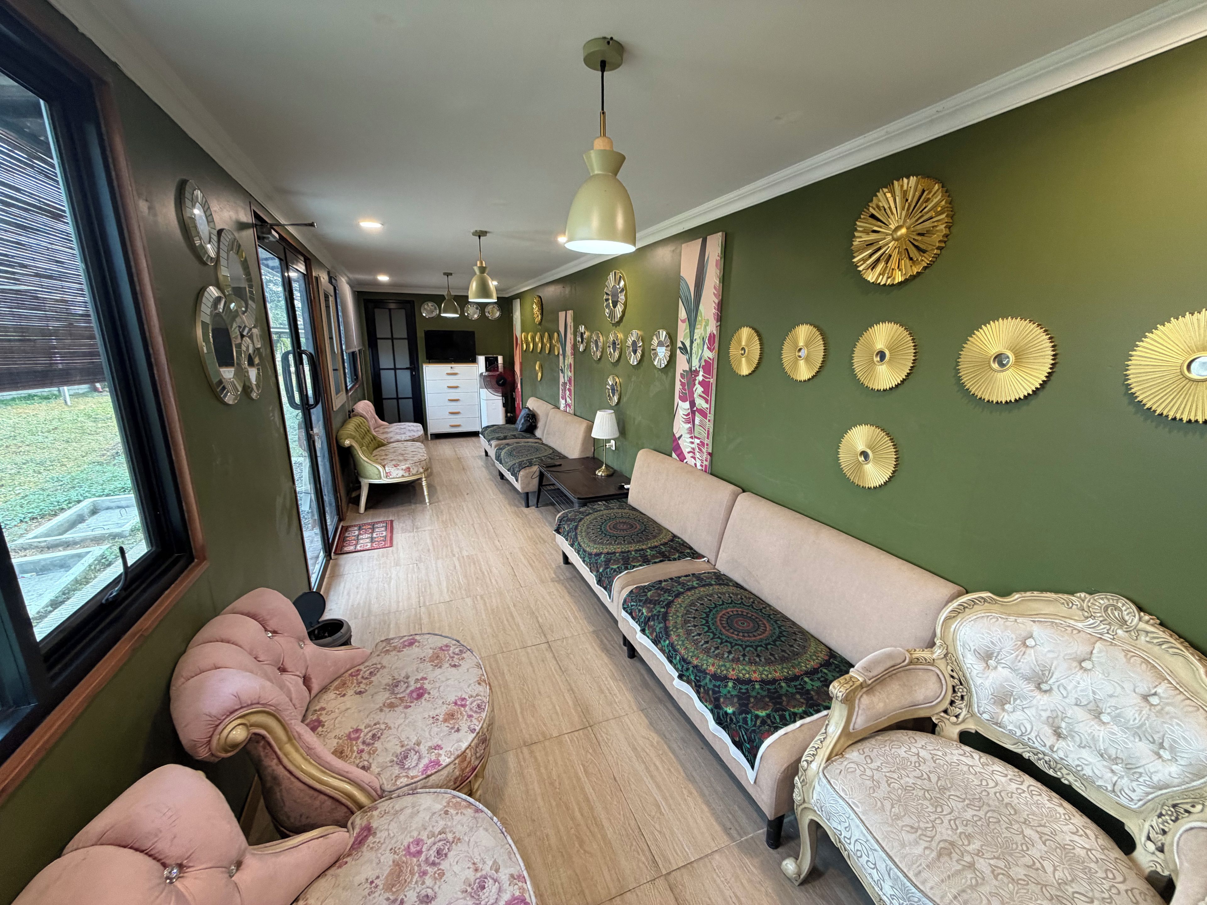 A room with a sofa, chairs, and a dining table. There are wall decorations and a window.