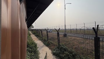 A pathway beside a fence with a streetlight and parked cars in the background.