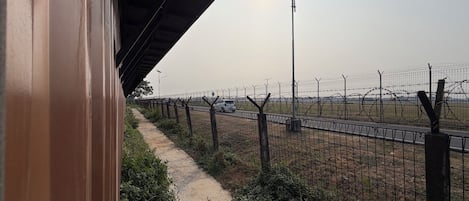 A pathway beside a fence with a streetlight and parked cars in the background.