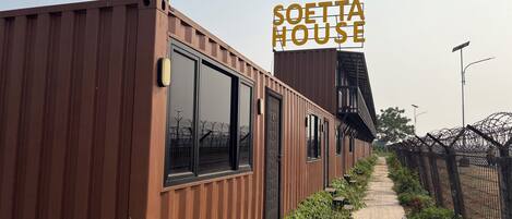 A modern building with a sign reading 'SOETTA HOUSE' and a pathway leading to it.