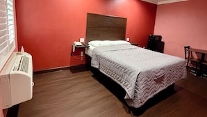 A bedroom with a bed, a bedside table, a heater, and a window with blinds. - HOLLYWOOD MOTEL (Los Angeles)