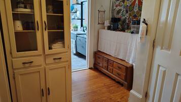 Een gang met een houten kast, een klein houten dressoir en een keuken in de achtergrond.