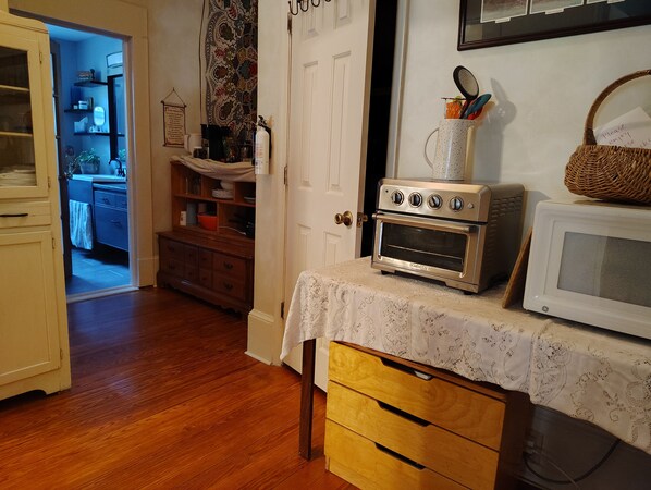 A kitchen with a microwave, oven, and a wooden cabinet.