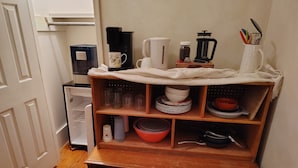 Una cocina con cafetera, hervidor, frasco de especias y molinillo de café sobre la encimera.
