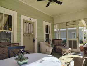 A covered porch with a table, chairs, and a ceiling fan.