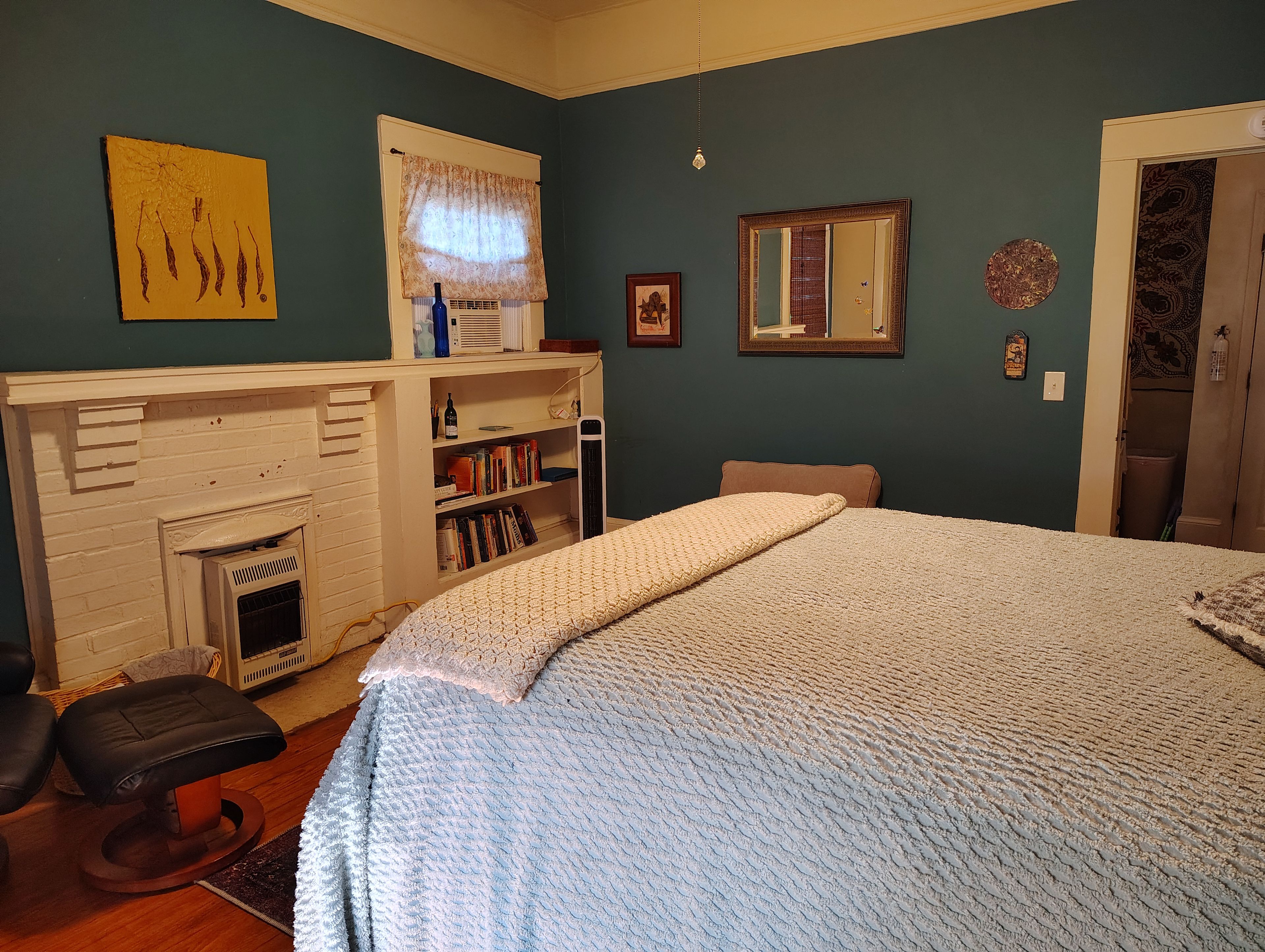 Un dormitorio con una cama grande, una chimenea, una estantería y un espejo.