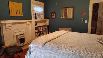 Un dormitorio con una cama grande, una chimenea, una estantería y un espejo.