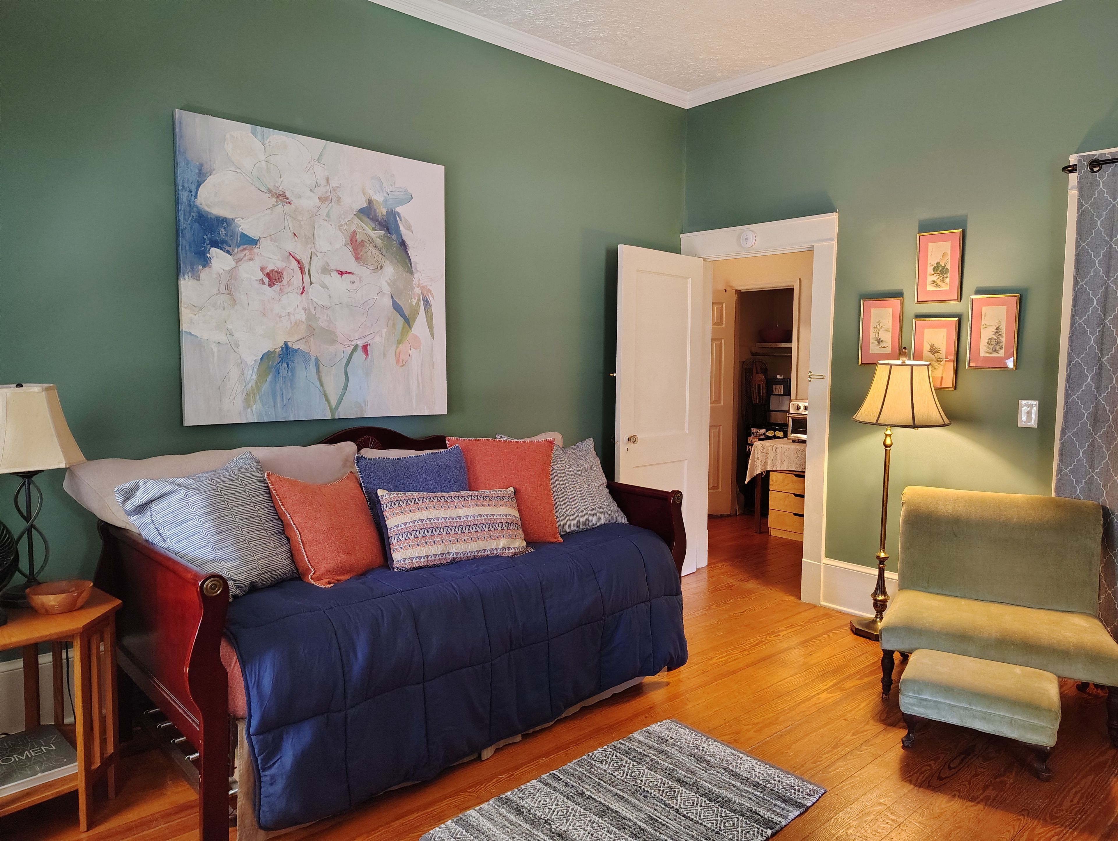 A living room with a blue sofa, a wooden coffee table, a lamp, and a painting on the wall.