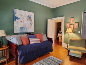 Un soggiorno con un divano blu, un tavolino in legno, una lampada e un quadro appeso al muro.