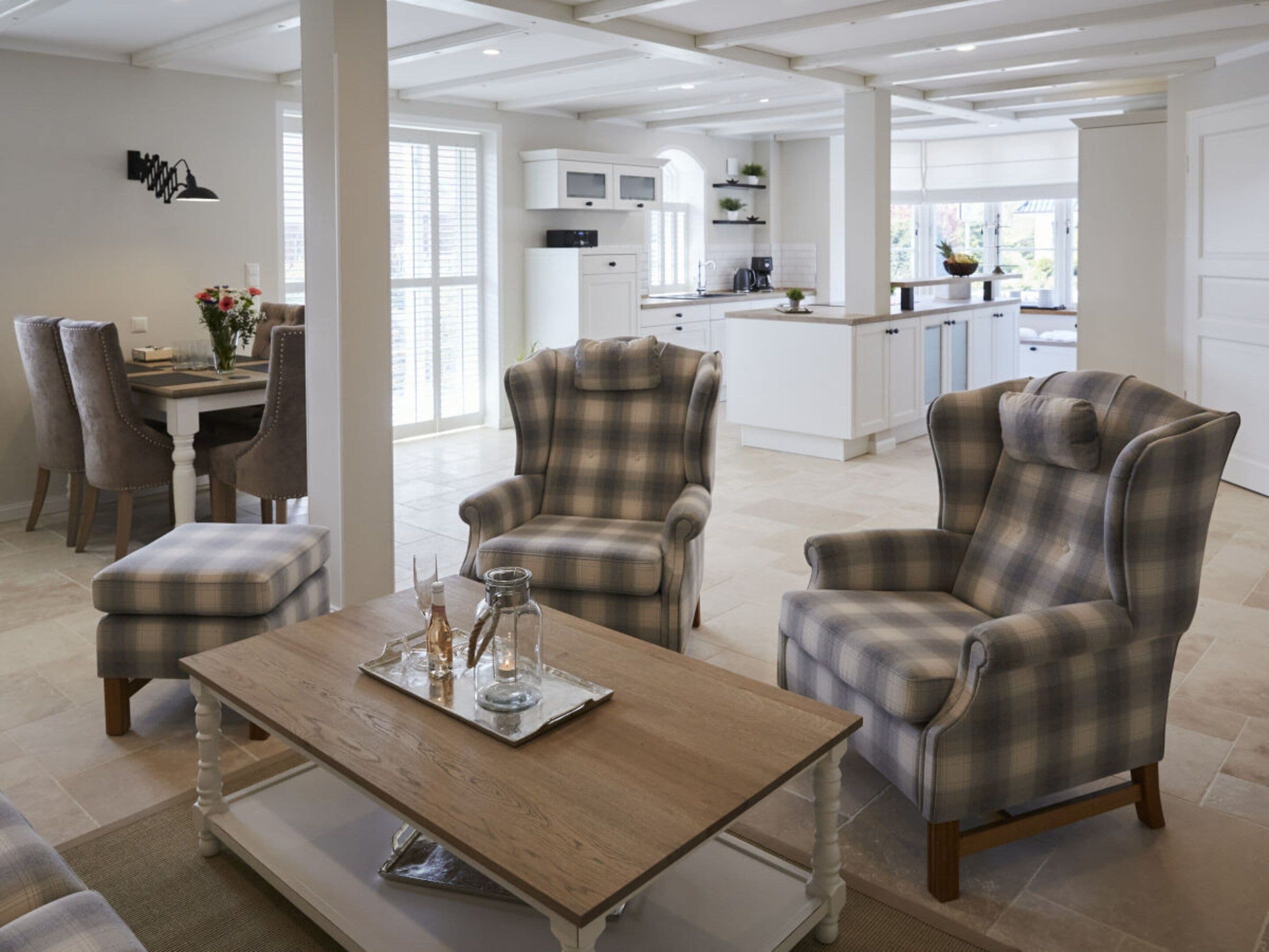 Een ruime woonkamer met een eethoek, twee fauteuils en een salontafel.
