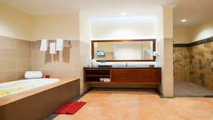 Un baño moderno con una bañera grande, un tocador de madera, un espejo y una pared de piedra.