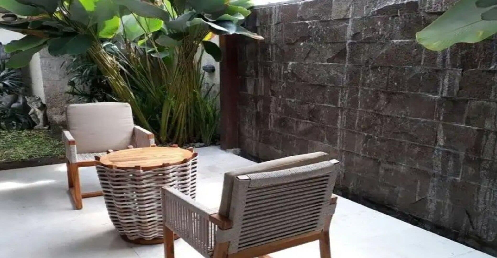 Un patio con mobiliario de mimbre, incluyendo una silla y una mesita redonda.