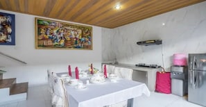 Un comedor con una mesa dispuesta para cuatro personas, una cocina con electrodomésticos modernos y un cuadro grande en la pared.
