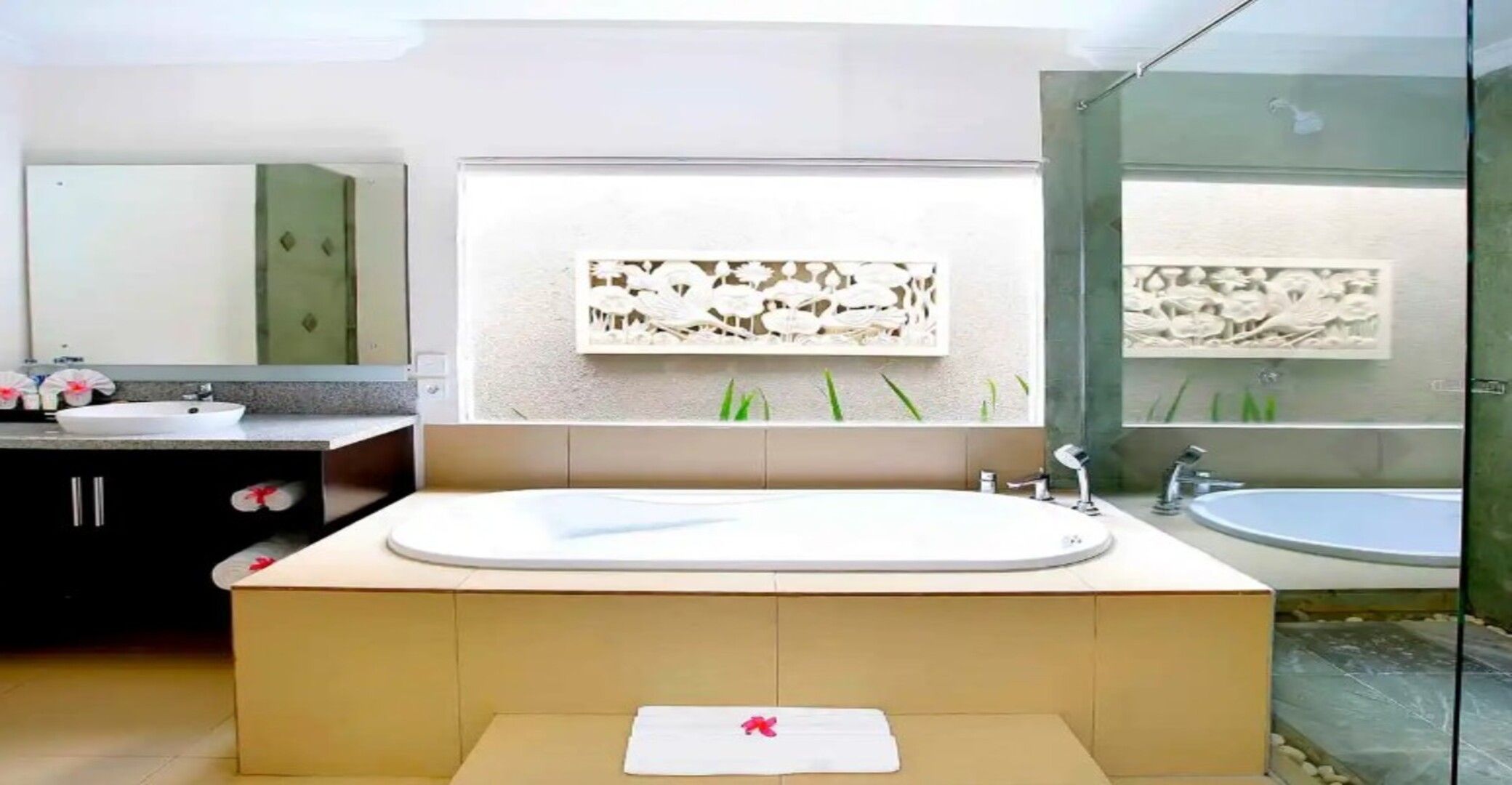 A modern bathroom with a large bathtub, a separate sink, and a glass shower enclosure.