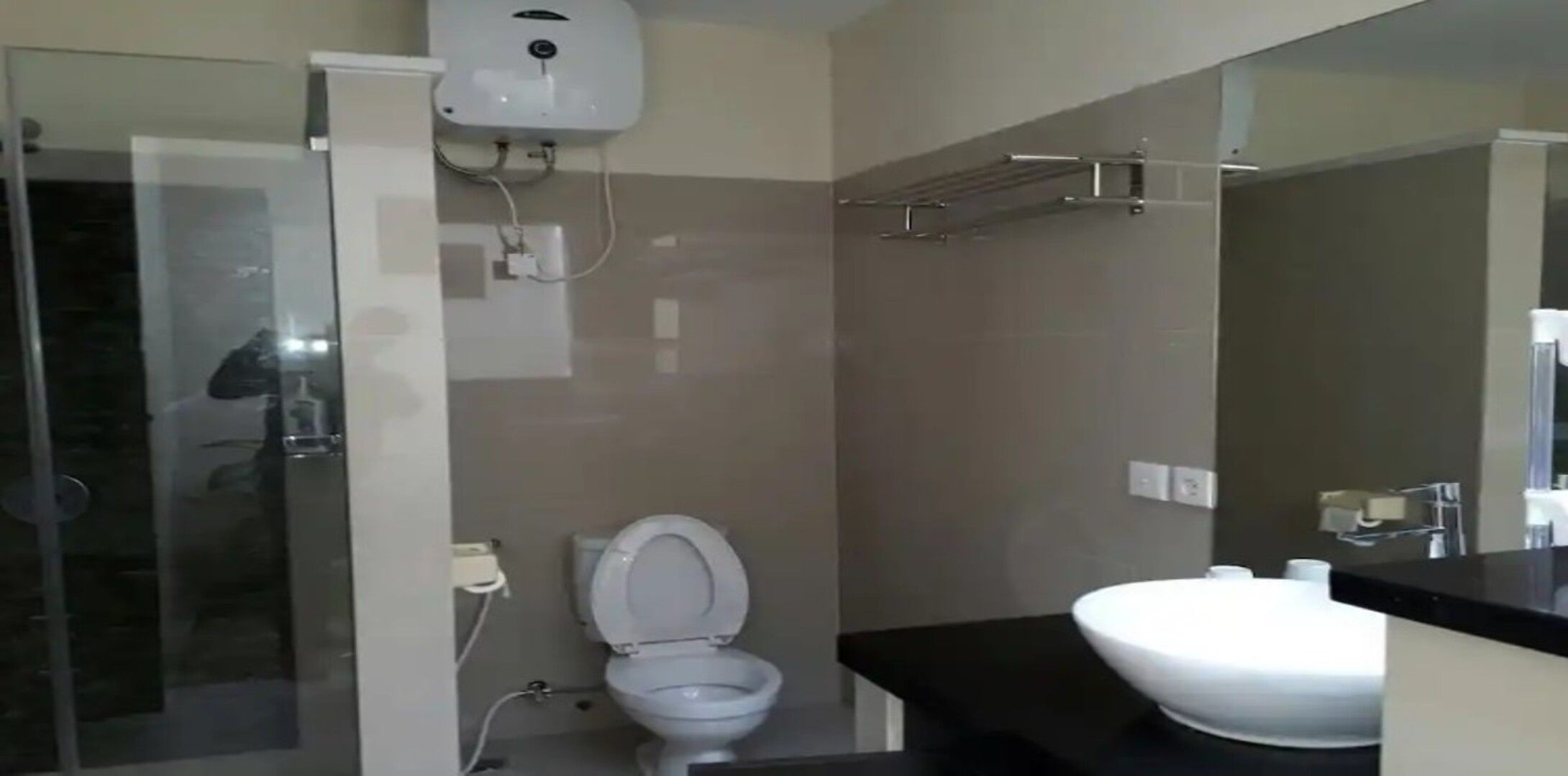 Un baño moderno con cabina de ducha de vidrio, inodoro blanco y encimera negra con lavabo blanco.