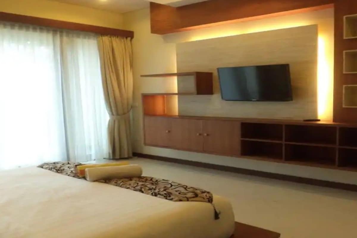 A hotel room with a large bed, a flat-screen TV mounted on the wall, and a built-in entertainment unit.