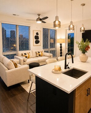 A modern kitchen with a central island, black faucet, and pendant lighting. - The Ivory Suite Midown (Atlanta)