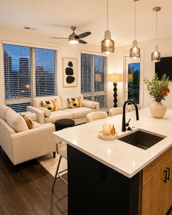 A modern kitchen with a central island, black faucet, and pendant lighting. - The Ivory Suite Midown (Atlanta)
