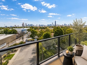 A balcony with a city view, a potted plant, and a candle on a table. - The Ivory Suite Midown (Atlanta)