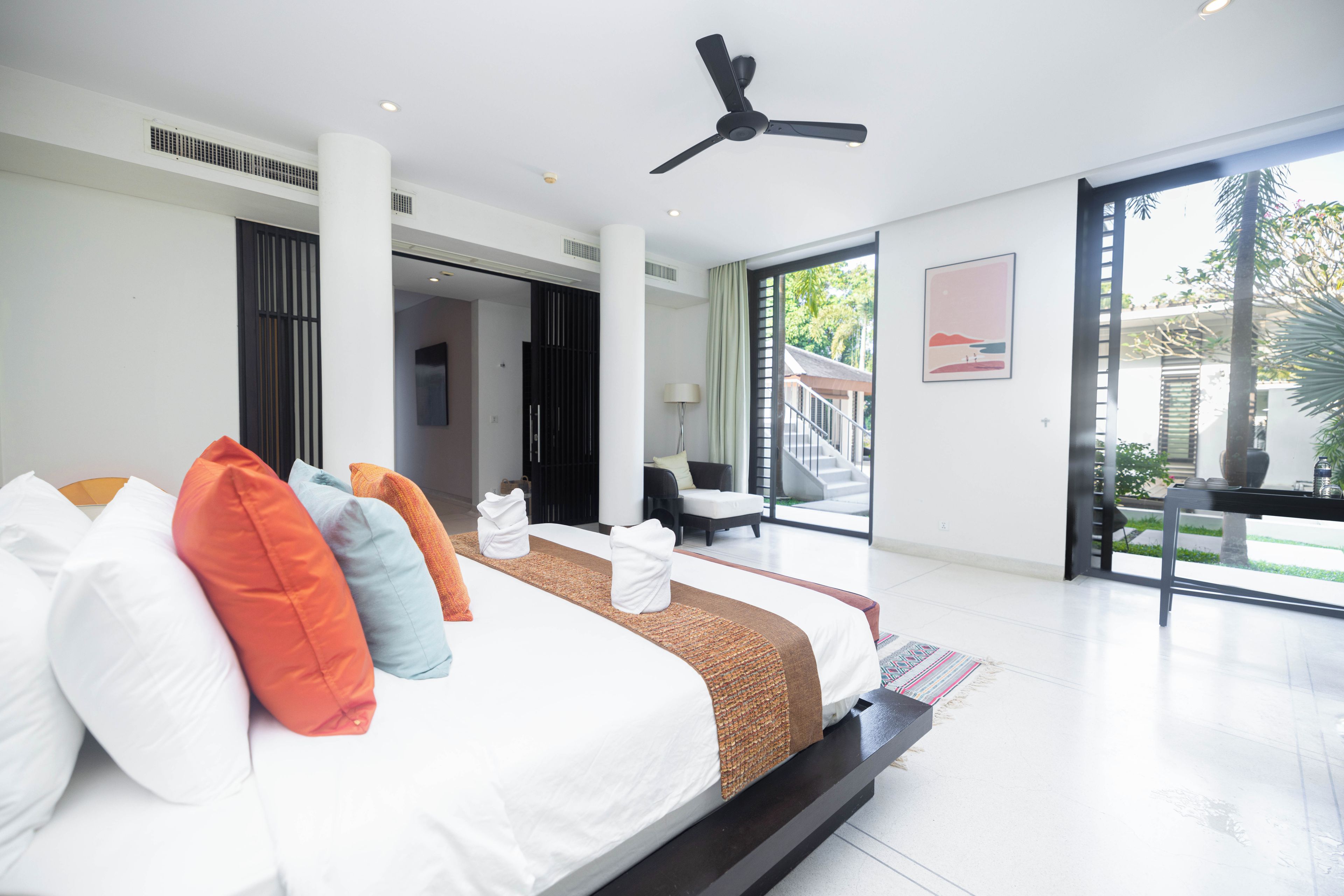 Un dormitorio moderno con una cama grande, un ventilador de techo y vistas al exterior.