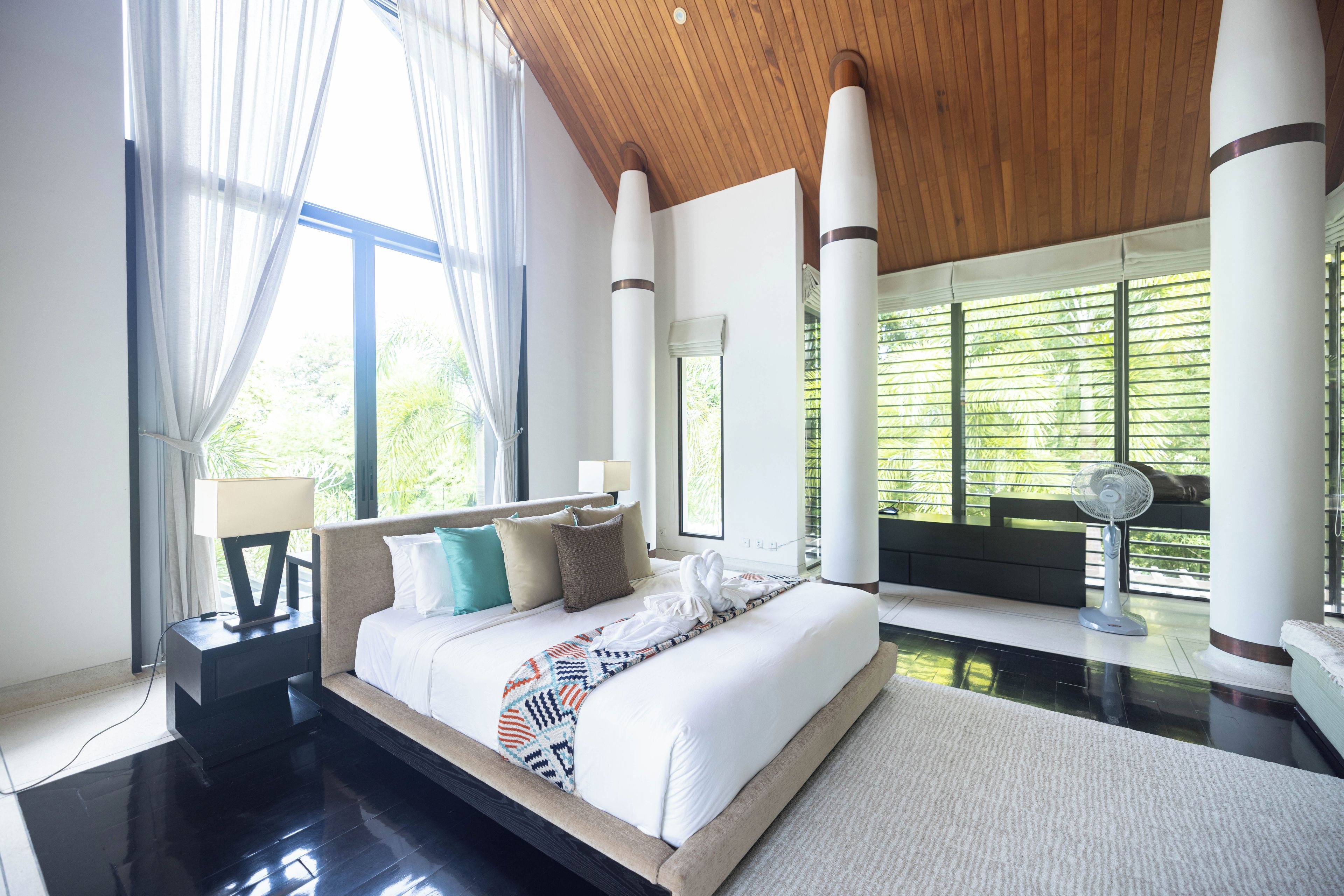 Habitación de hotel moderna con una cama grande, un área de descanso y vistas a zonas verdes.