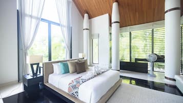 Habitación de hotel moderna con una cama grande, un área de descanso y vistas a zonas verdes.