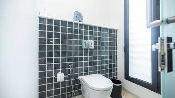 Un baño moderno con inodoro, bidé y un cubo de basura.