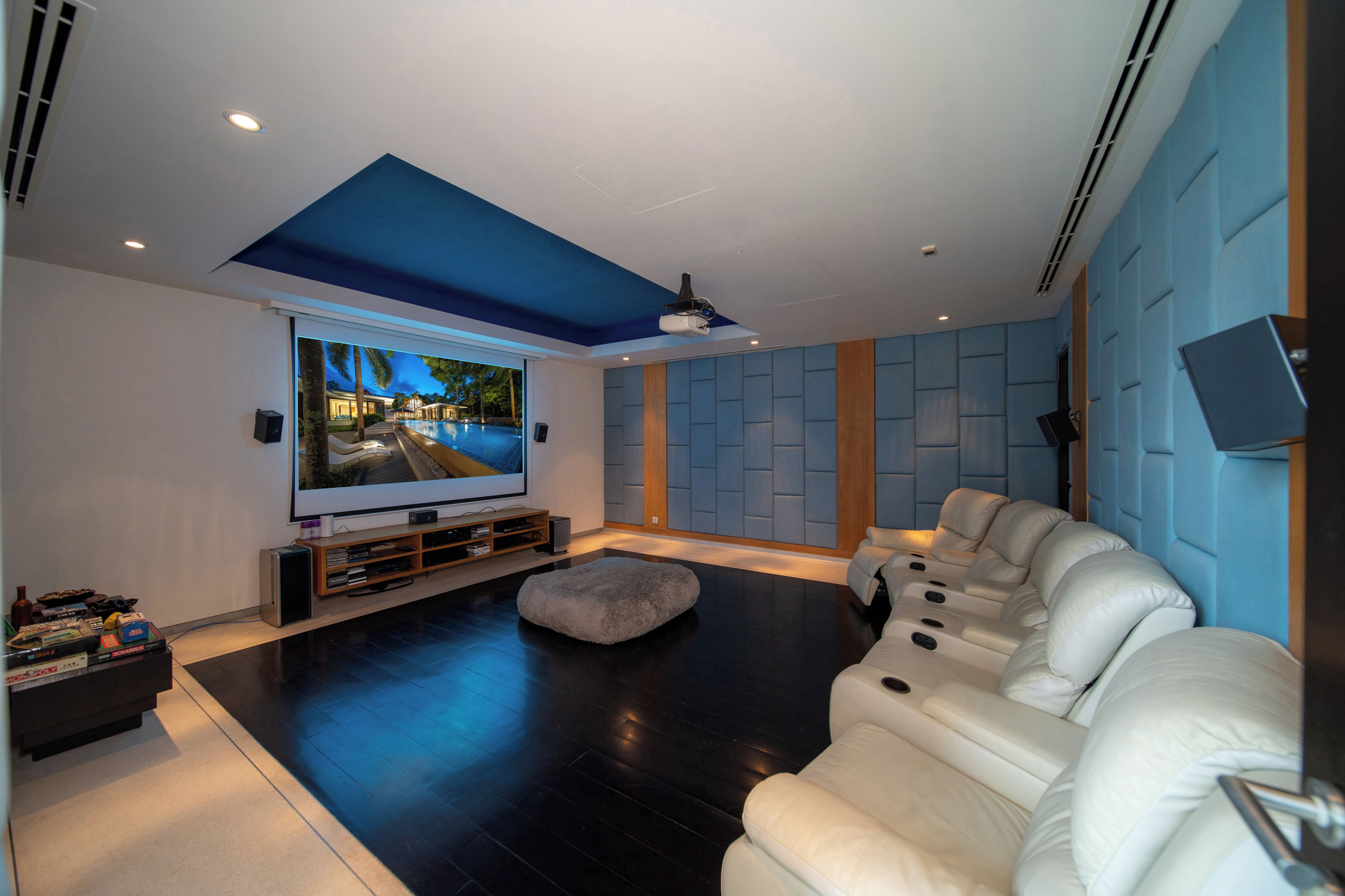 Un salon moderne avec un téléviseur à écran plat, un canapé en cuir blanc et une grande fenêtre.