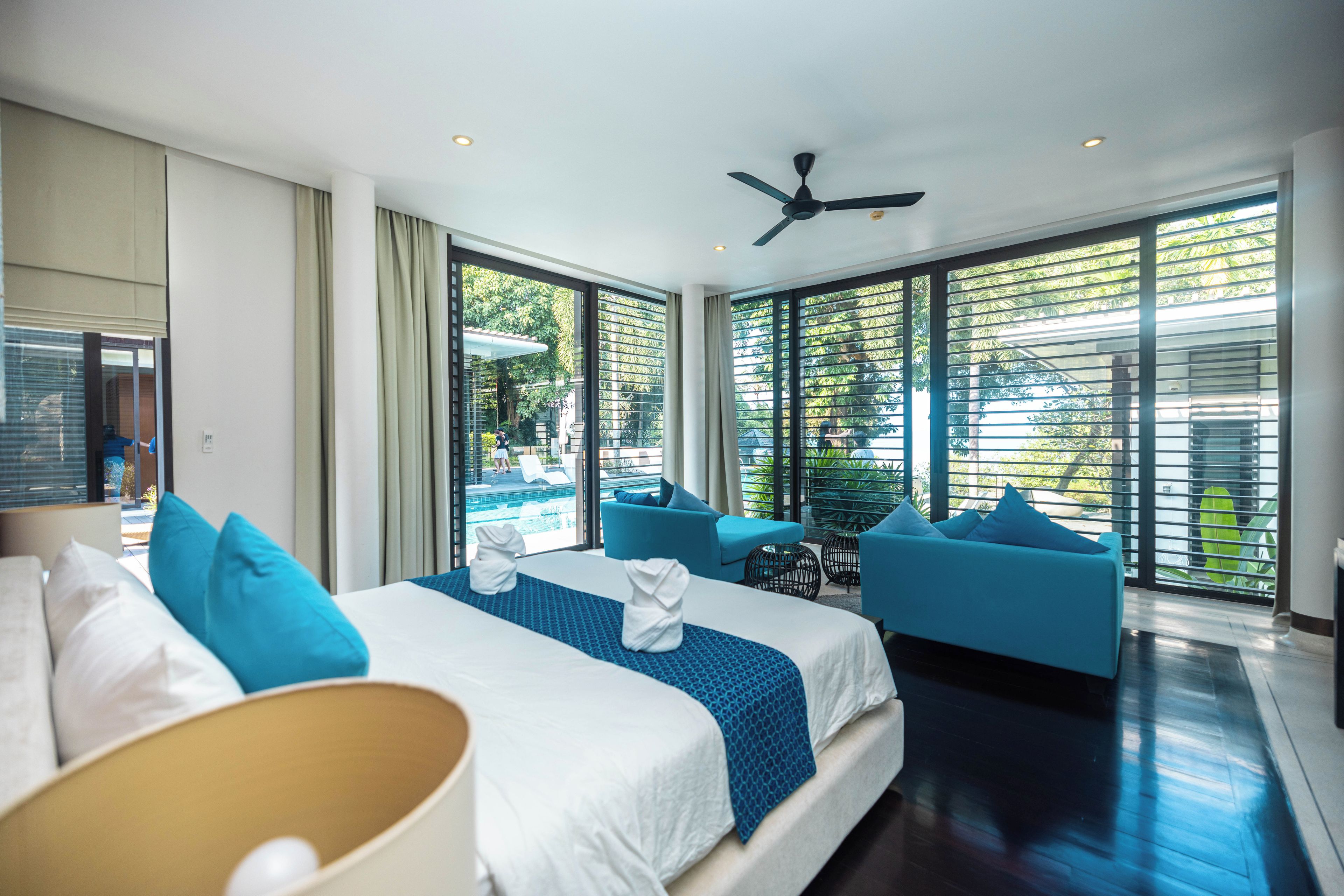 Ein Hotelzimmer mit einem Bett, einer Couch, einem Deckenventilator und großen Fenstern.