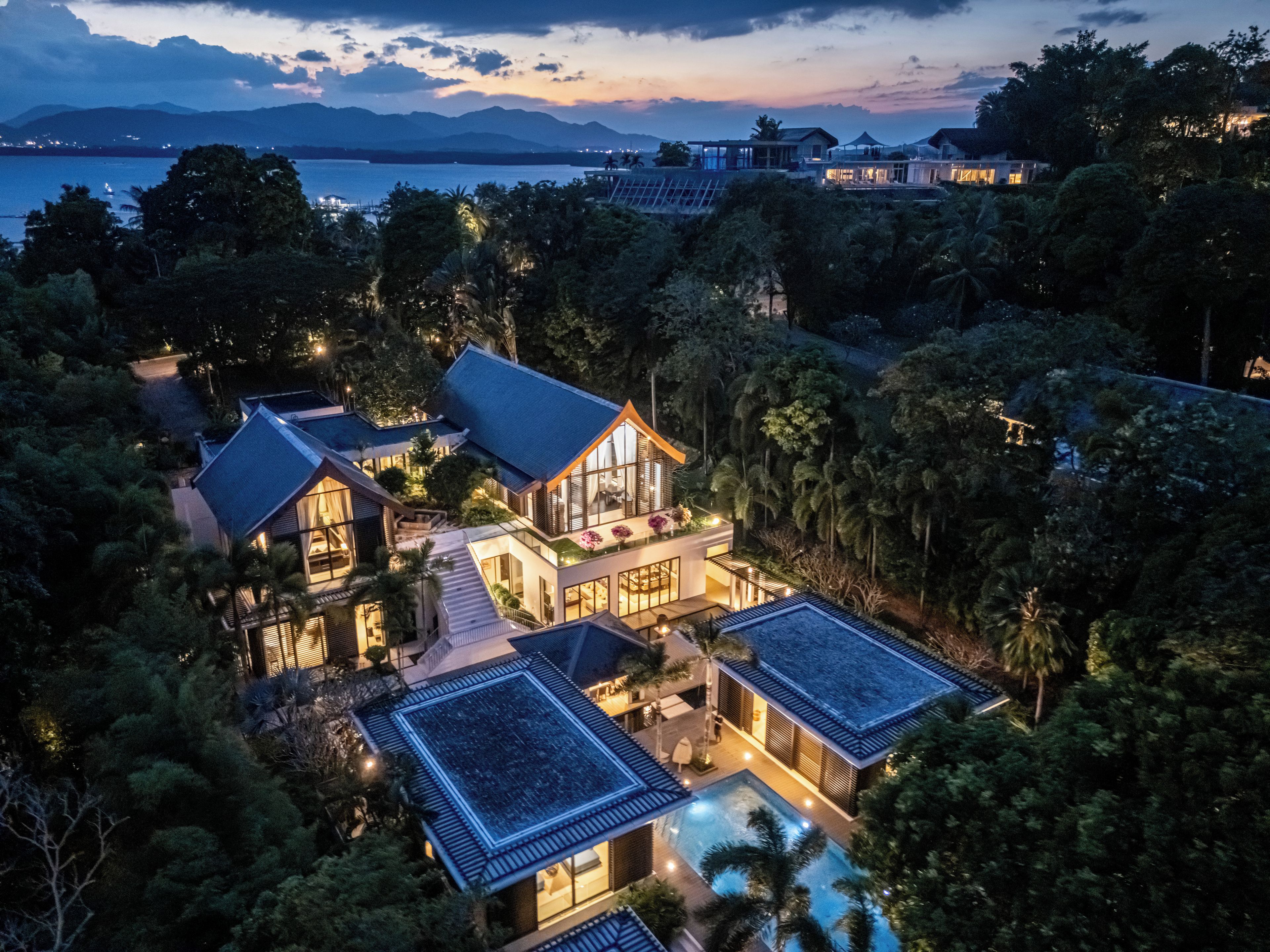 A luxurious villa with multiple buildings, a swimming pool, and a view of the sea.