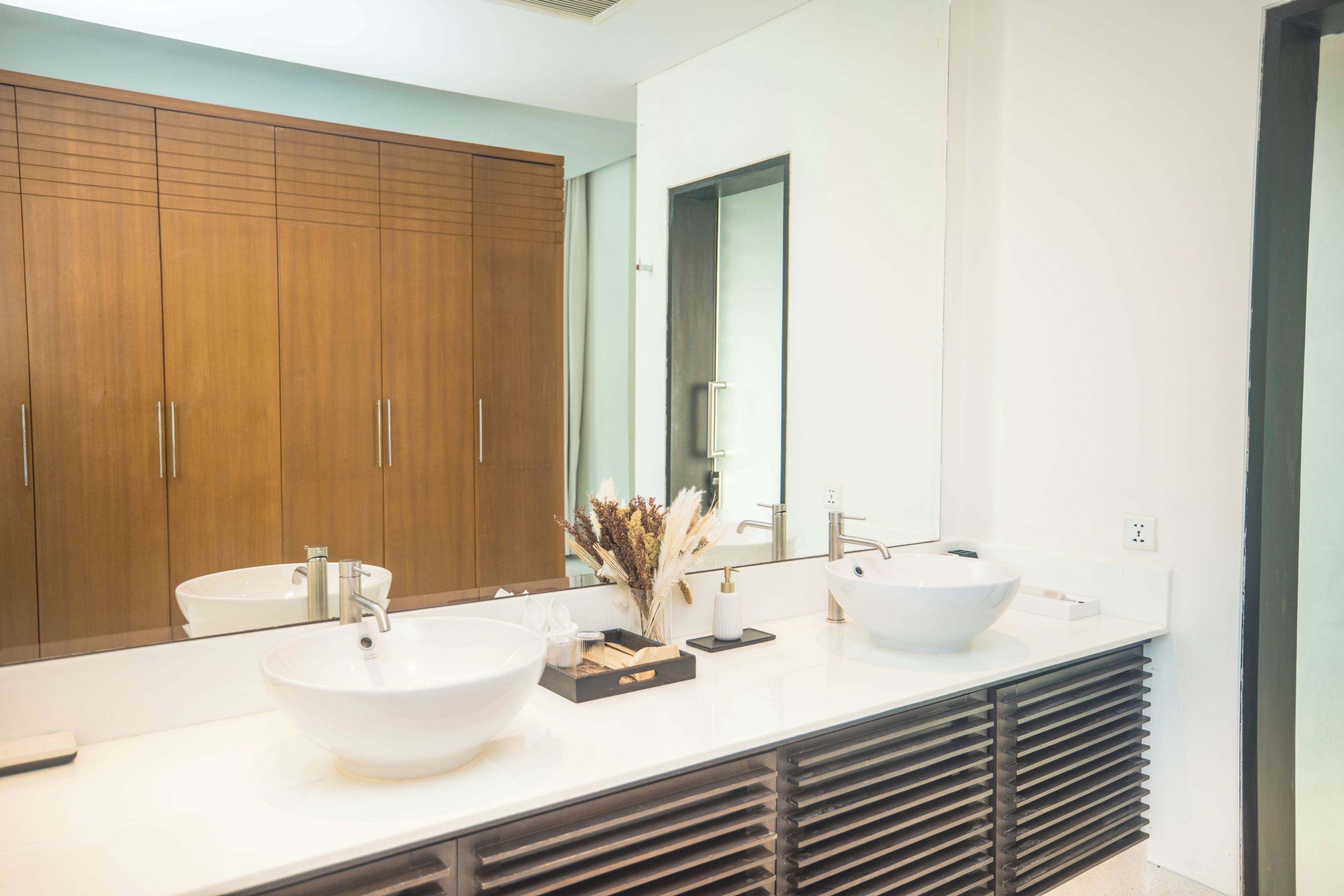 A modern bathroom with two sinks, a large mirror, and wooden cabinets.