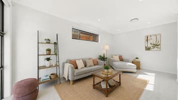 A modern living room with a sofa, a coffee table, and a bookshelf.