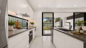A modern kitchen with white cabinetry, stainless steel appliances, and a view of the backyard.